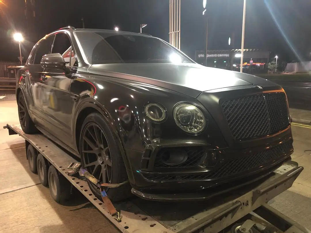 A dark Bentley Bentayga on an ICM trailer at night