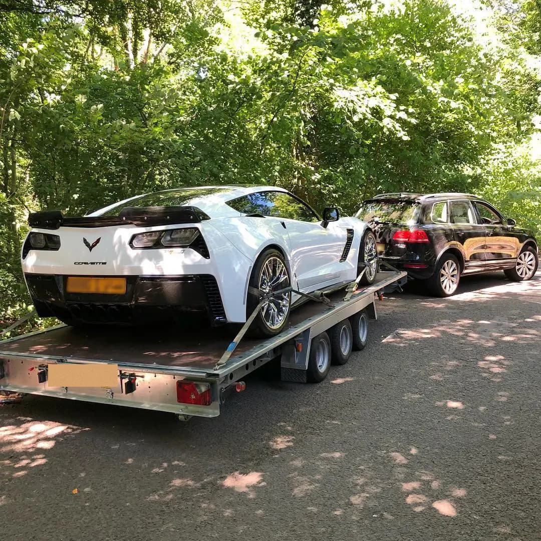 A white Corvette on the deck of an ICM multi-car transporter