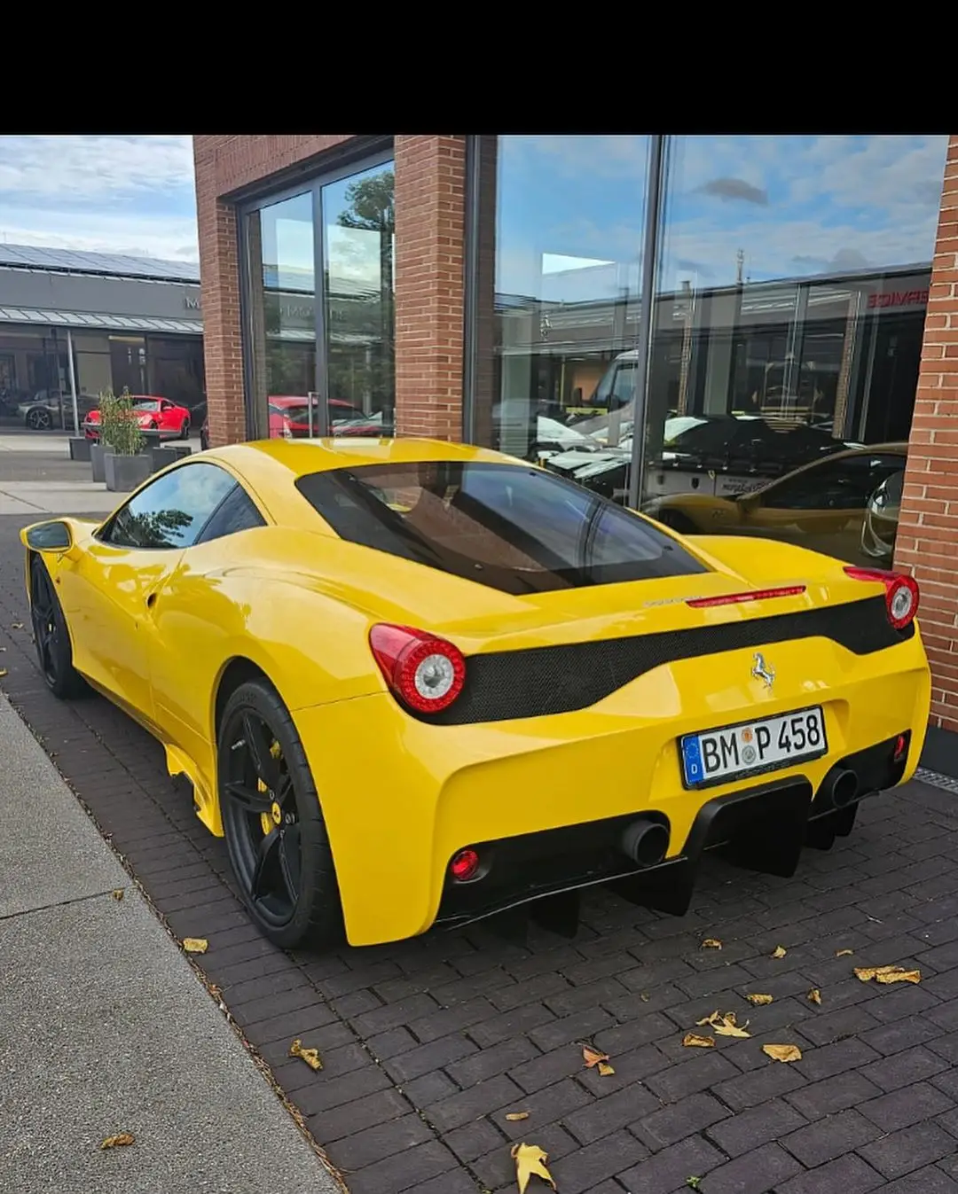 A yellow Ferrari 458 Speciale on German plates, parked on cobbles after delivery