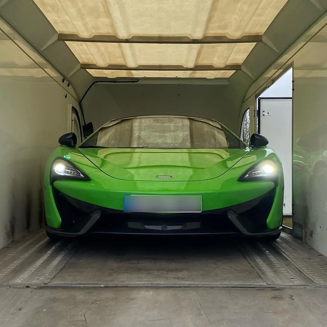 A green McLaren 720S secured inside an ICM enclosed transporter, photographed from the rear doors