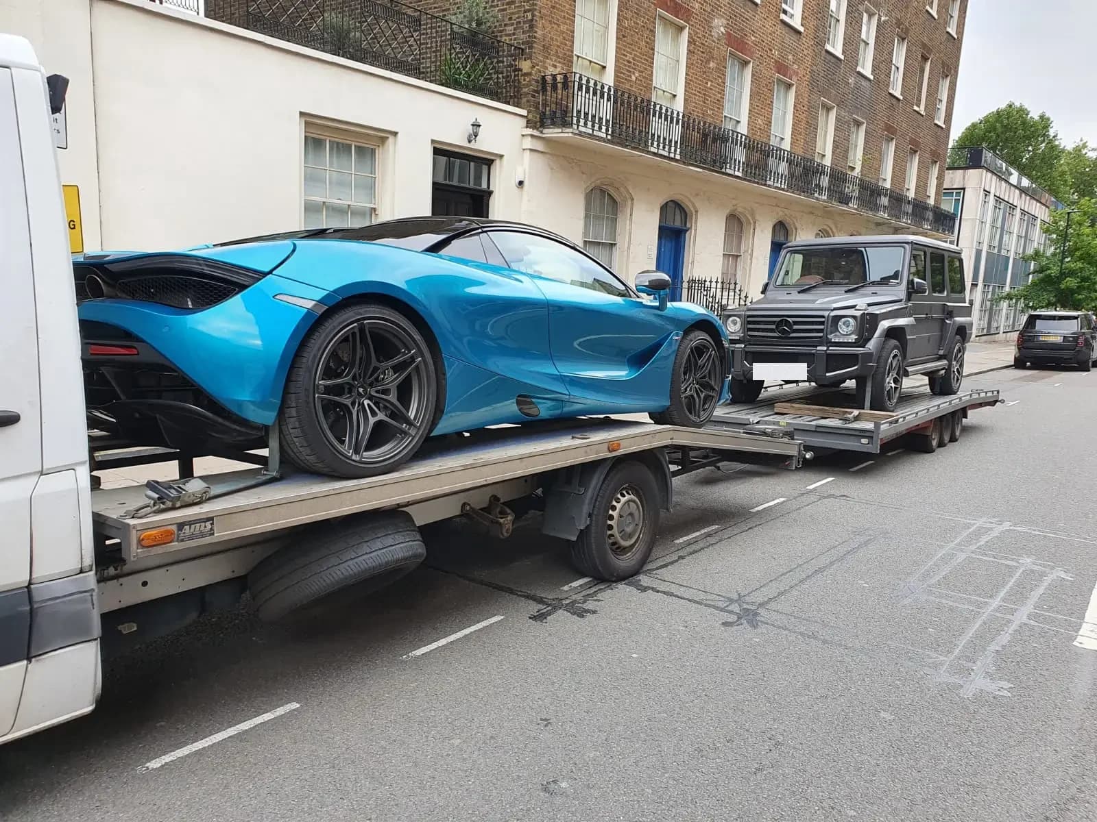 A McLaren and a G-Wagon secured together on an ICM transporter in London