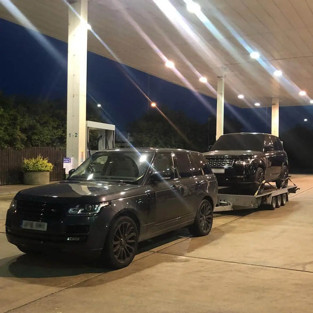 Two Range Rovers parked under a lit marquee at night before an event movement