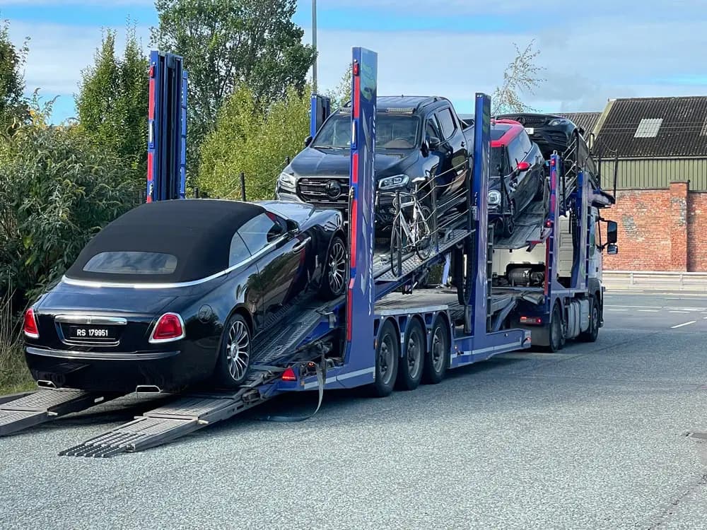 A dark saloon being loaded onto an ICM multi-car transporter