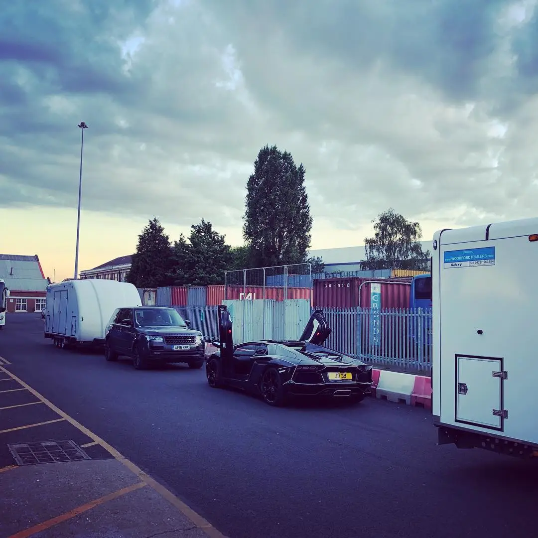An ICM transporter loaded with cars at dusk under a heavy sky